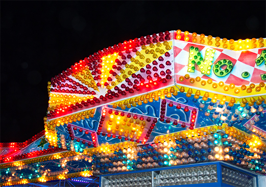 Carnival rides and festival lights fill the fairgrounds during a community celebration.