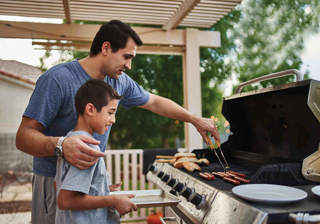 A man and a child using a propane-powered grill together.