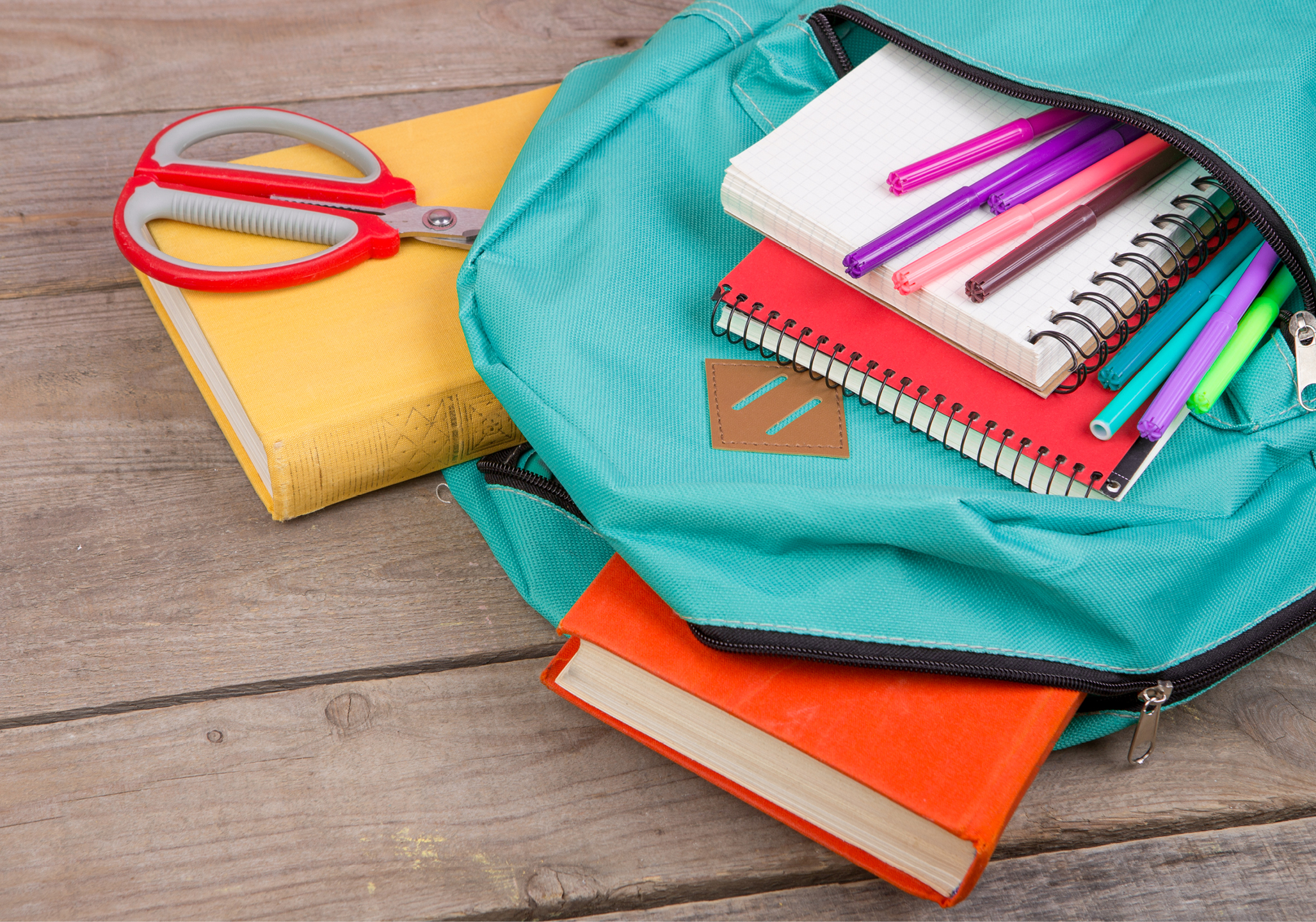 Children’s backpack filled with a variety of school supplies.