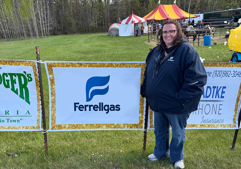 Ferrellgas employee stands near a sponsorship sign at Mayfest.
