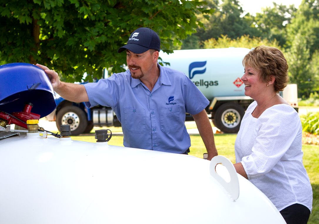 A Ferrellgas Delivery Driver showing a customer what is underneath the lid of her propane tank.