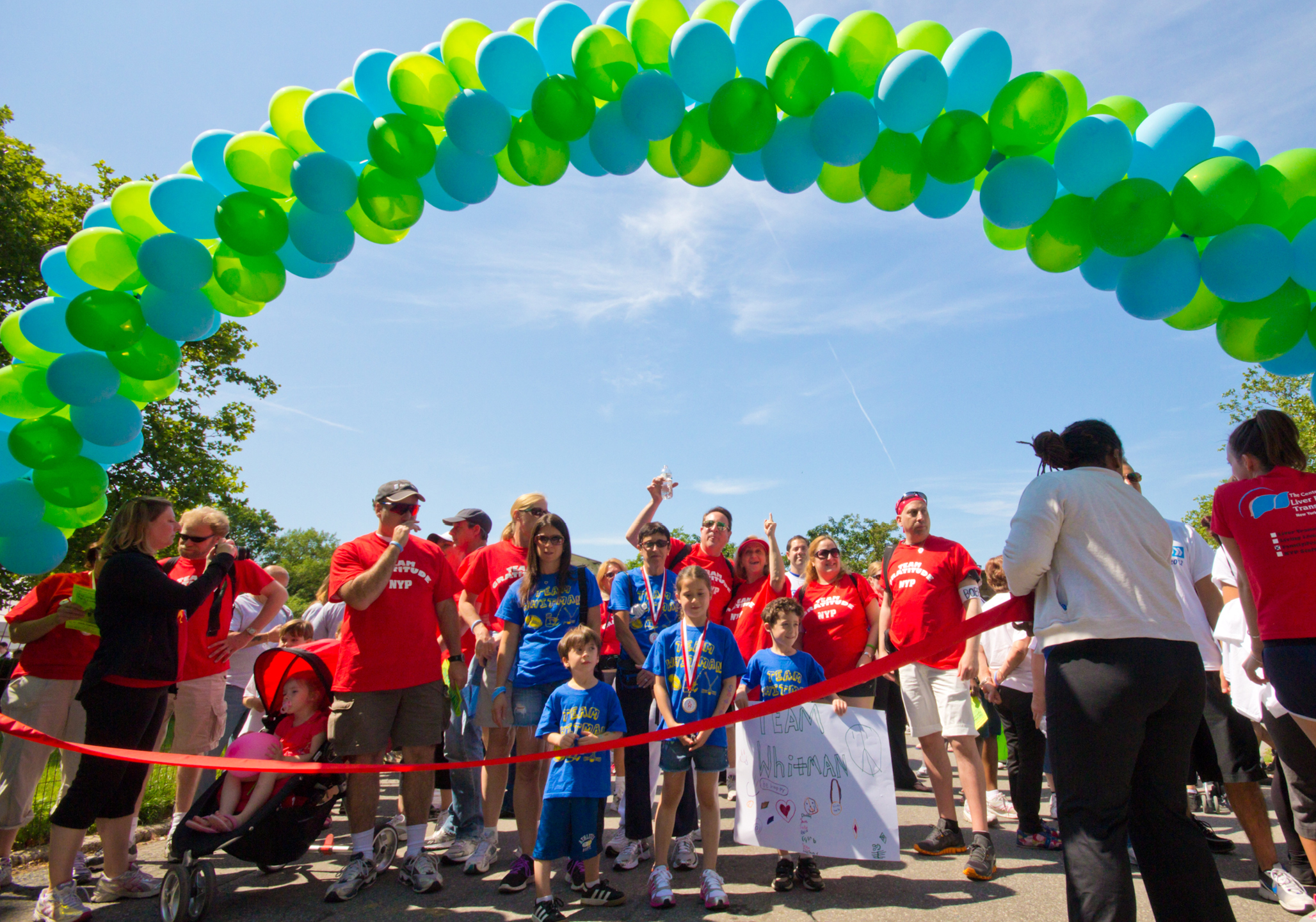 Balloon arch and ribbon at the finish line of the run with people pictured.