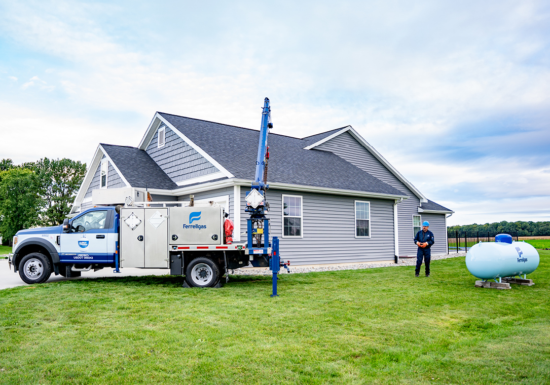 A Ferrellgas Service Technician stands near a newly set residential propane tank.