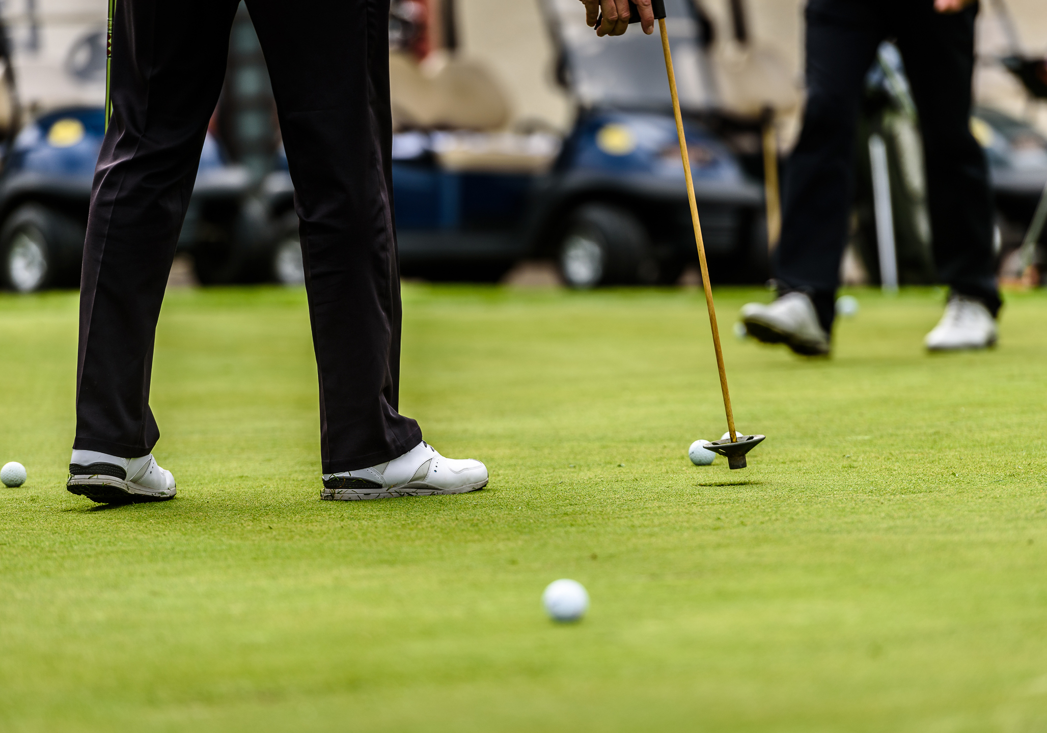 Person using a golf club hitting a golf ball.