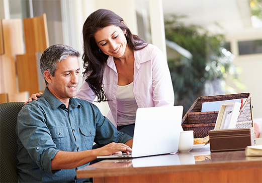 A man and woman appear happy while looking at a computer screen.